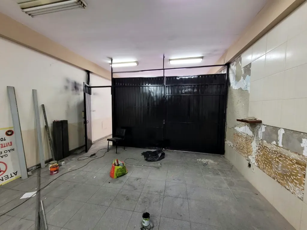 Portão de chapa preto fechando o fundo de um salão