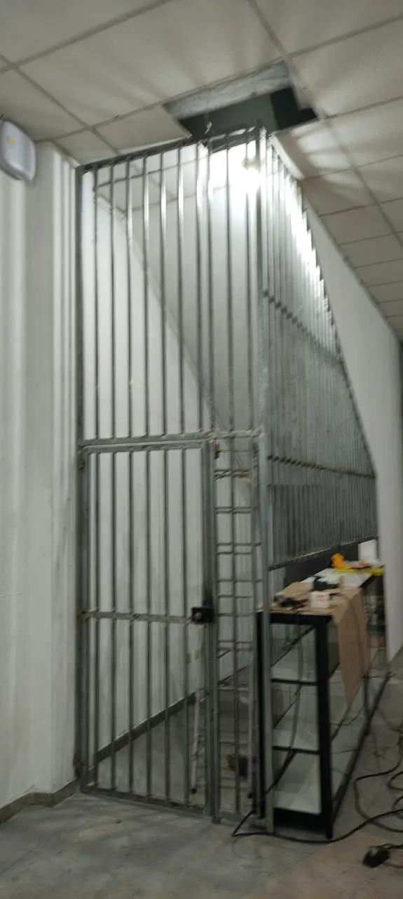 Grade com porta fechando o acesso a uma escada interna