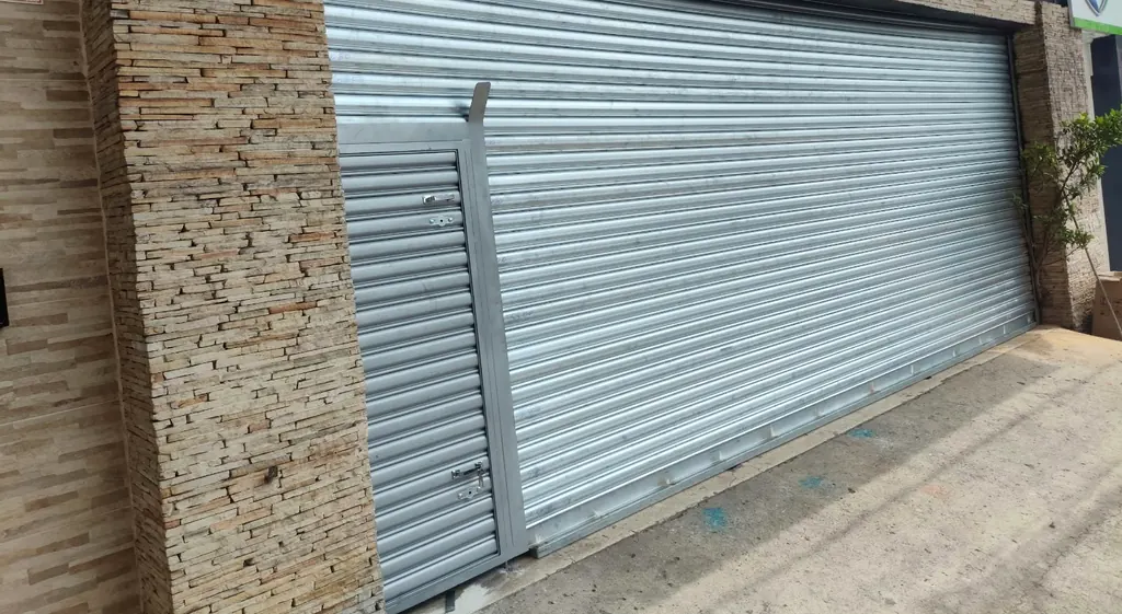 Porta de aço com portinhola numa loja com fachada de pedra